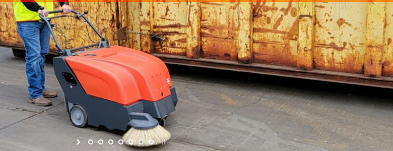 Operator using a PowerBoss walk-behind sweeper outdoors